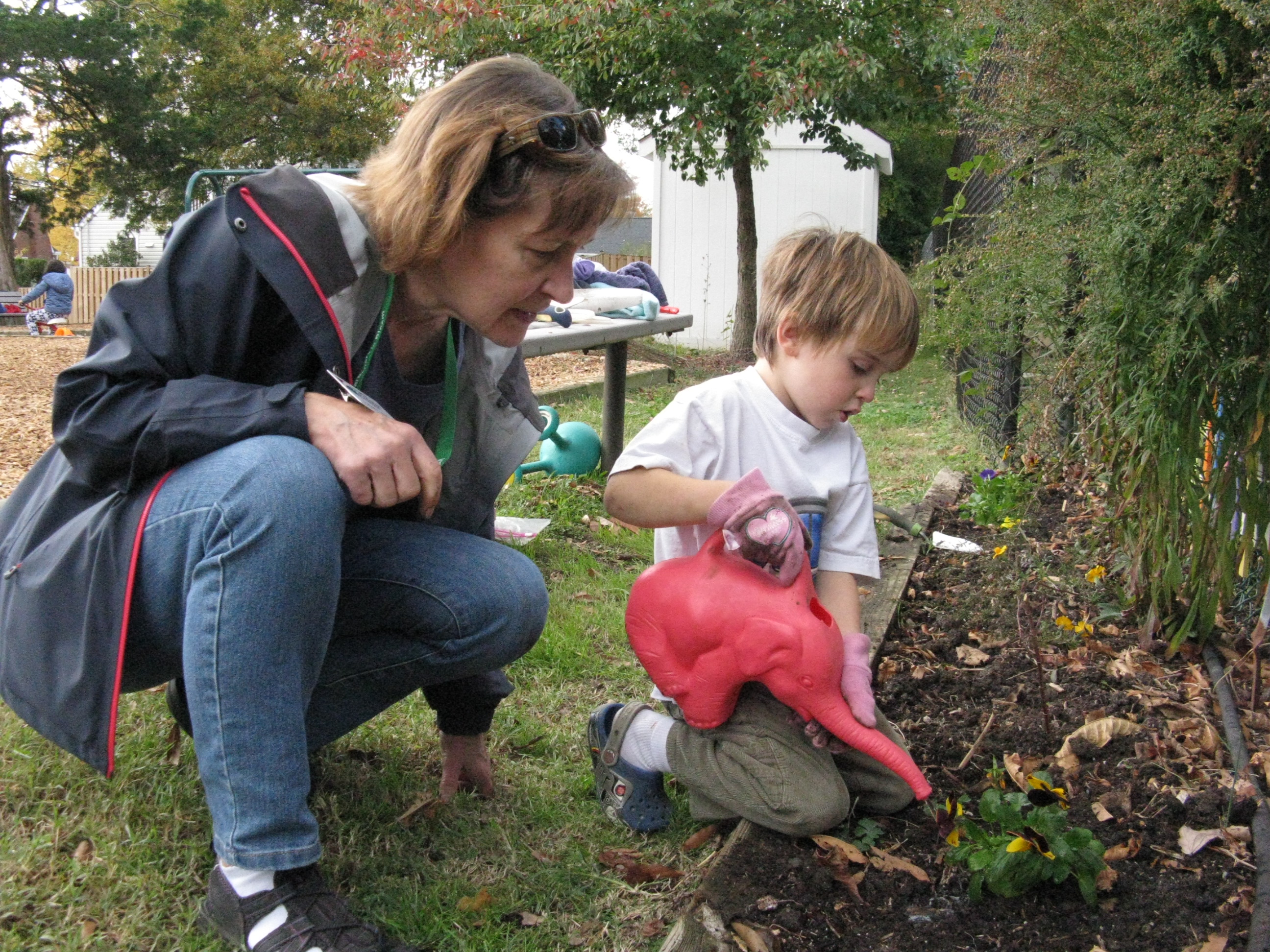 Master Gardener Susan Lewis with Carlin Hall Pre-Schooler, watering in the pansies