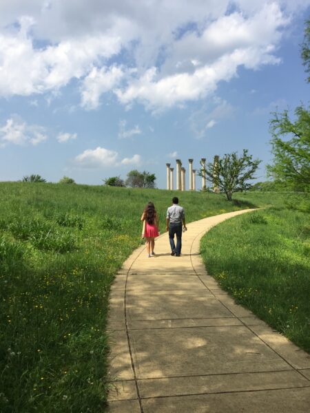 Visitors stroll on a winding path through the meadow to the Capitol Columns.