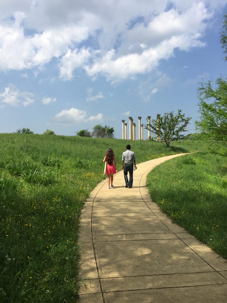 Visitors stroll on a winding path through the meadow to the Capitol Columns.