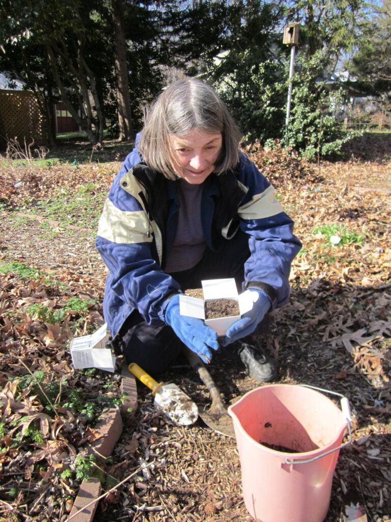 Woman crouching on ground filling in soil test box