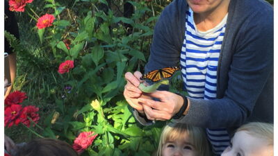 Volunteer with children and monarch butterfly