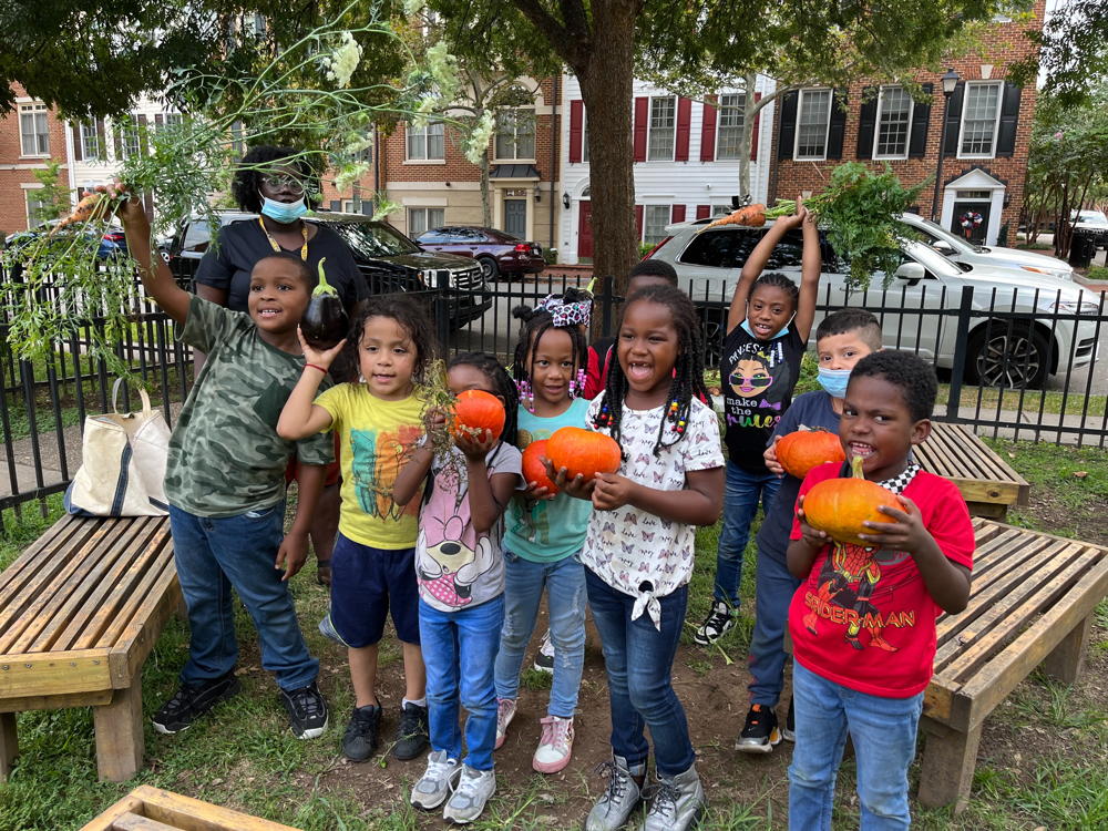 Group of children holding pumpkins they grew.