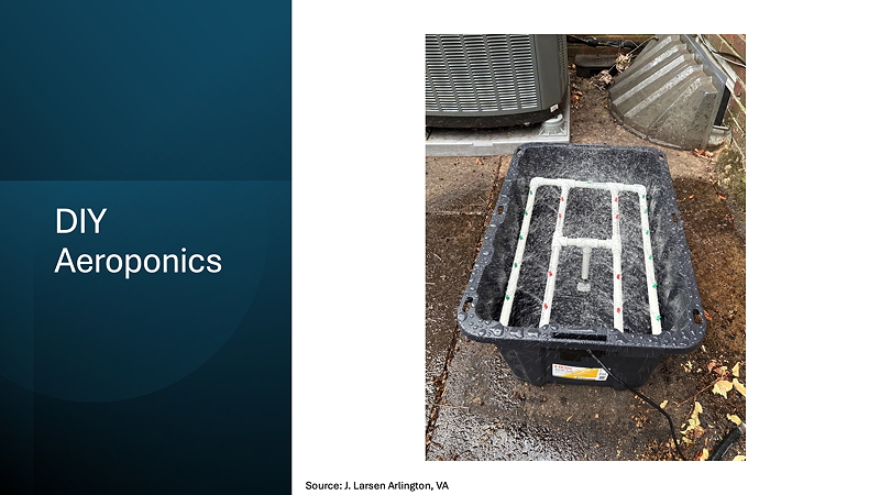 A plastic container set up for DIY aeroponics, with a white framework for plant support, placed on a concrete surface with additional equipment in the background.